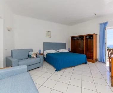 La camera familiare con letto matrimoniale, divano e armadio in legno